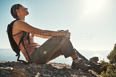Buy stock photo Shot of a young woman taking a break while out on a hike through the mountains