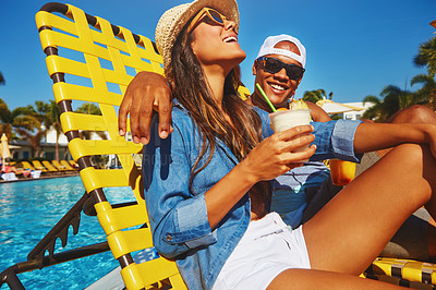 Buy stock photo Cropped shot of an affectionate young couple enjoying a few drinks poolside