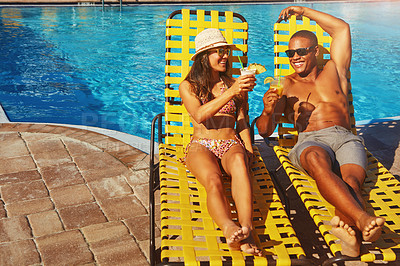 Buy stock photo High angle shot of an affectionate young couple enjoying a few drinks poolside
