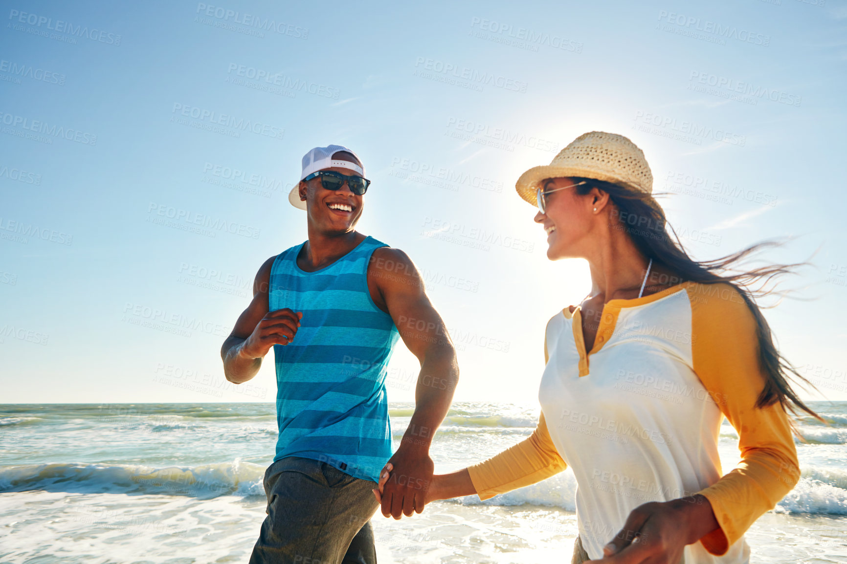 Buy stock photo Shot of a happy young couple taking a walk on the beach