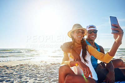 Buy stock photo Shot of a happy young couple taking a selfie on the beach