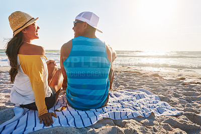 Buy stock photo Shot of a happy couple sitting on the beach on a sunny day