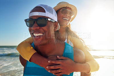 Buy stock photo Shot of a young man piggybacking his beautiful girlfriend on the beach