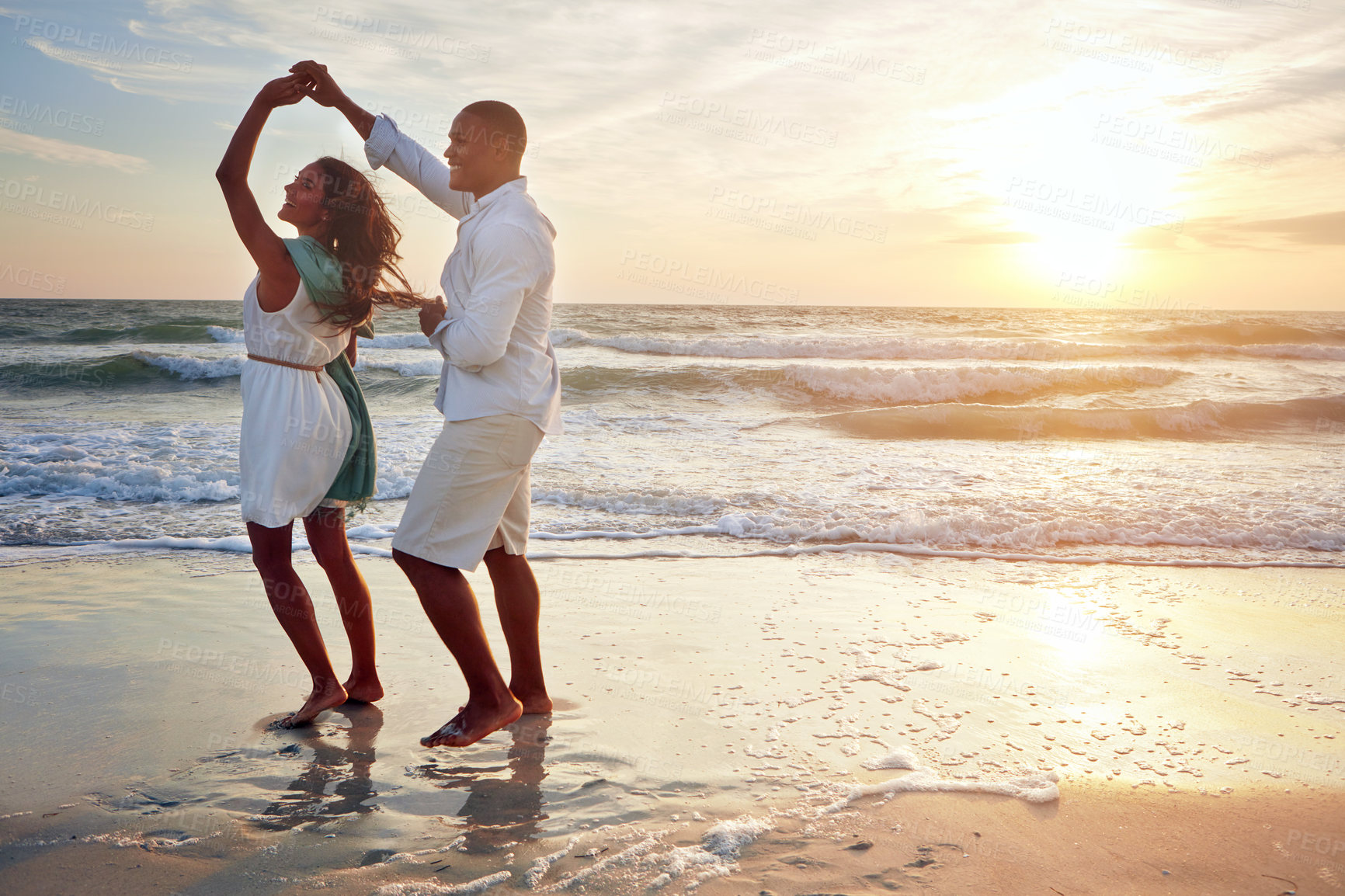 Buy stock photo Shot of a romantic couple dancing on the beach at sunset