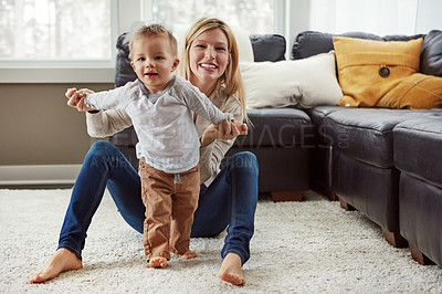 Buy stock photo Shot of a proud mother holding her little boy as he takes his first steps