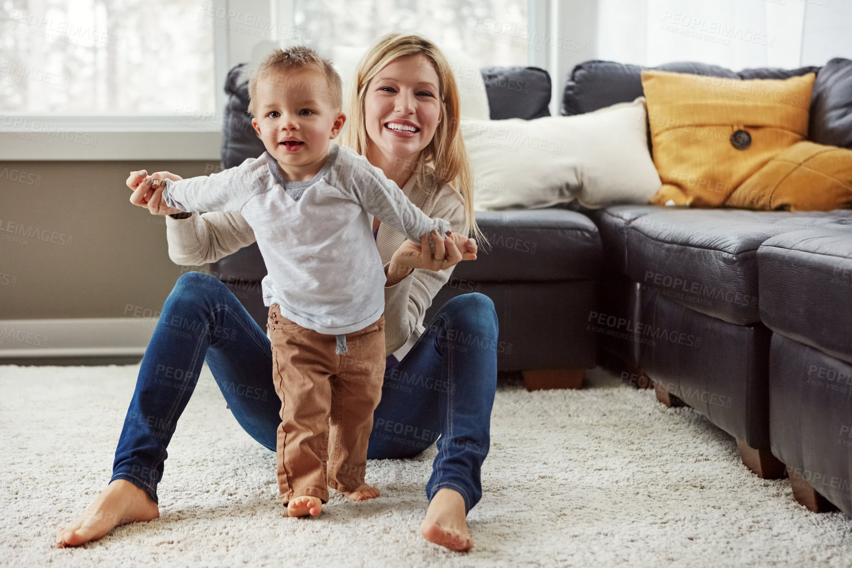 Buy stock photo Shot of a proud mother holding her little boy as he takes his first steps