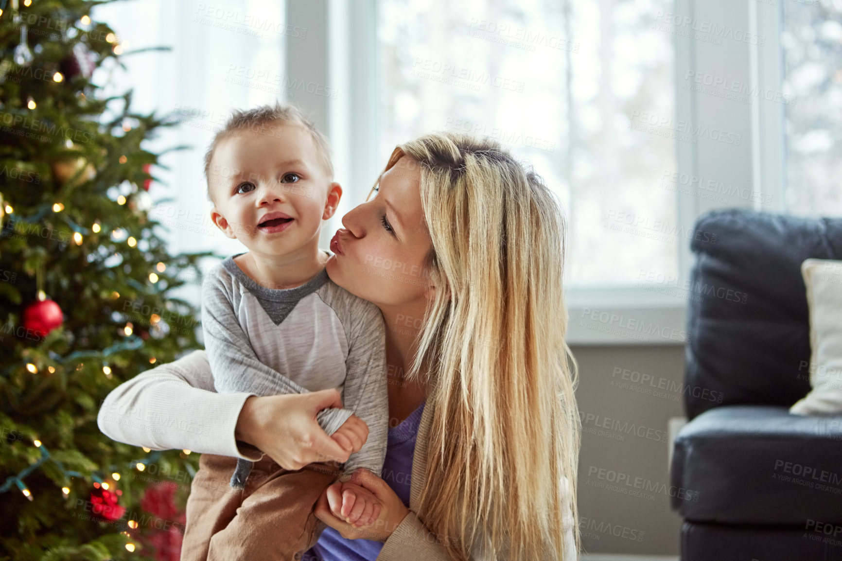 Buy stock photo Love, child and woman kiss for christmas, tree and laugh for bonding celebration together. Smile, trust for baby and family sit on floor, motherhood happiness and festive hugs for toddler at home