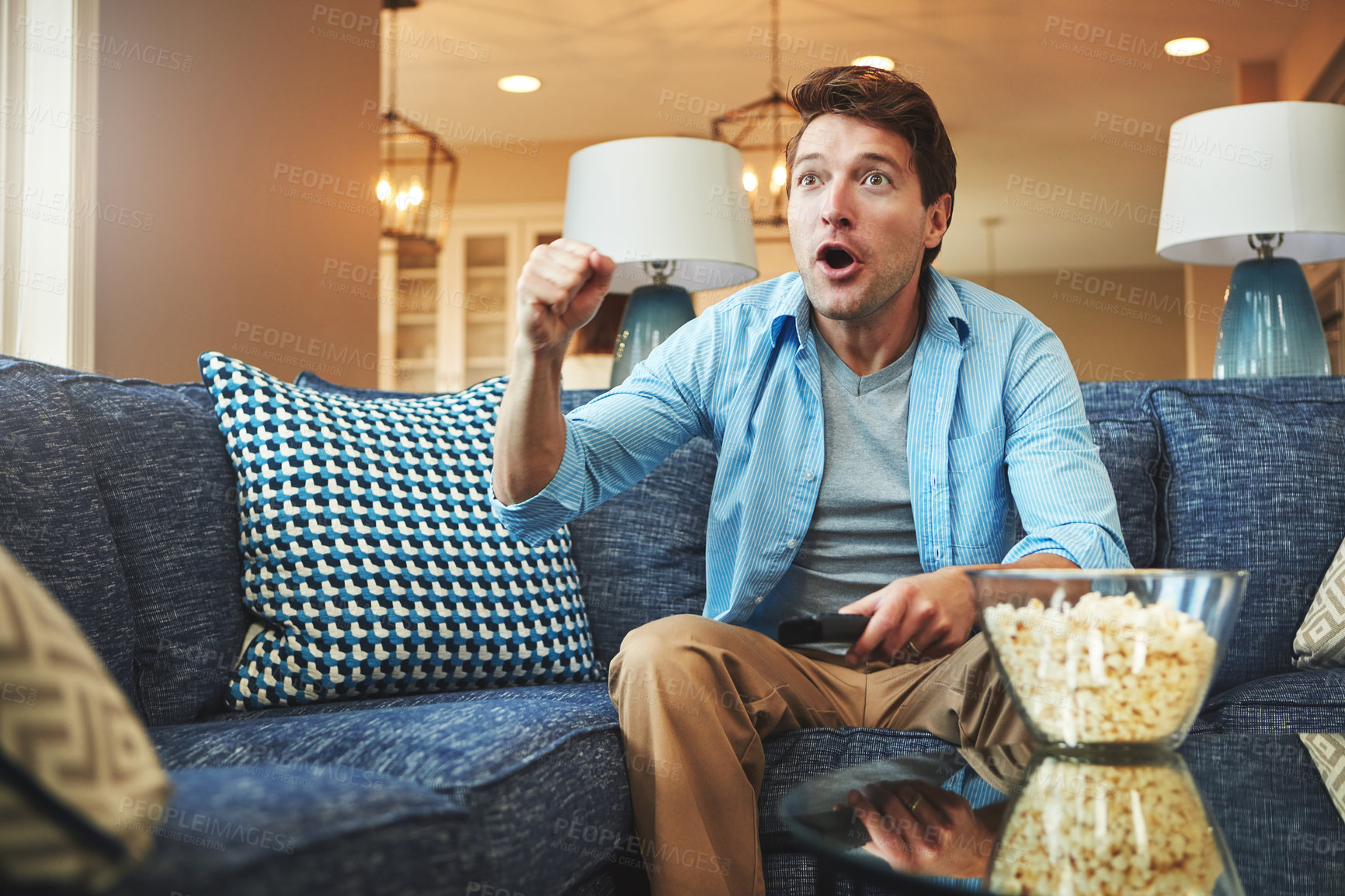 Buy stock photo Shock, popcorn and man on couch with remote for watching tv, streaming football game and omg for red card. Guy, sofa and surprise for sport team announcement in home with live television broadcast
