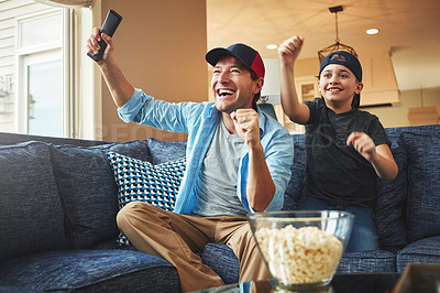 Buy stock photo Shot of an enthusiastic father and son watching a sports match on tv at home