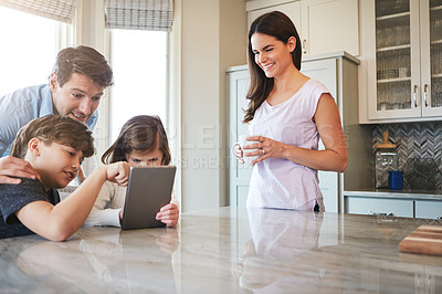 Buy stock photo Shot of a married couple and their young children playing with a tablet together in their kitchen