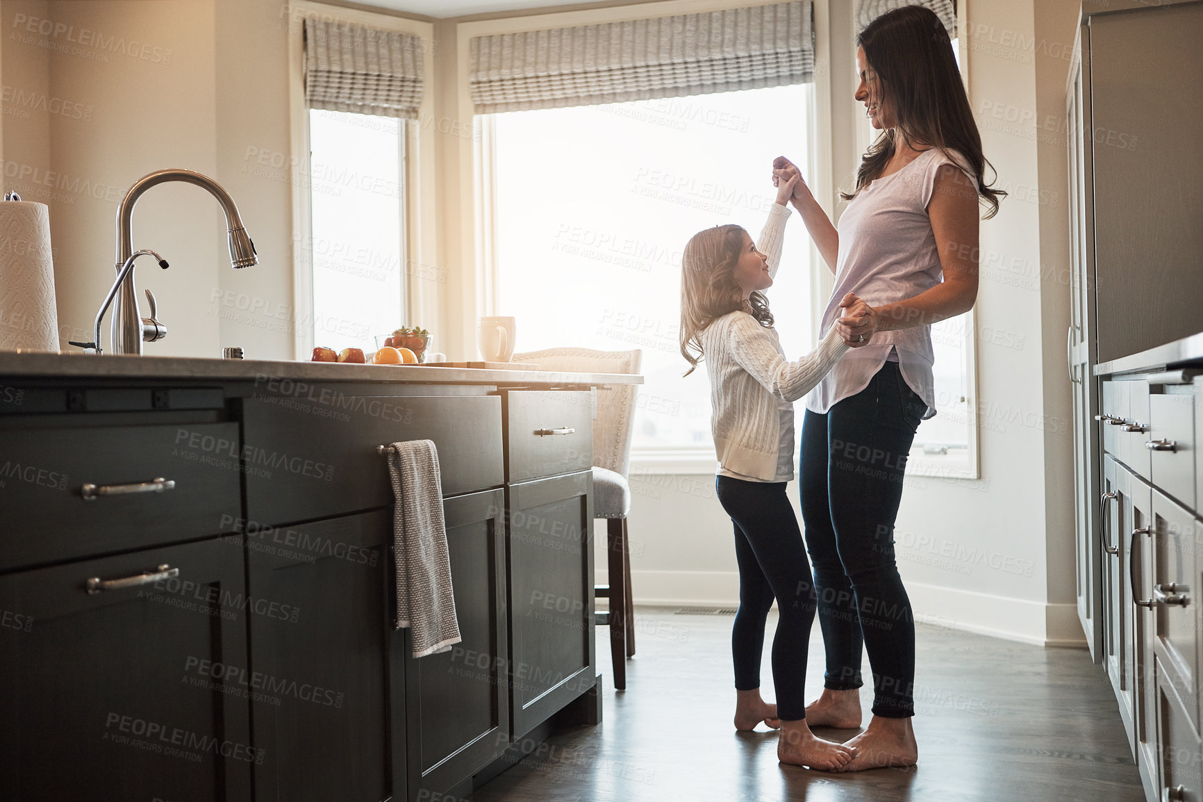 Buy stock photo Mother, daughter and dancing in kitchen, happiness and love in house, care and feet of kid on mom. Home, fun and smile for bonding in apartment, teaching and morning for support and holding hands