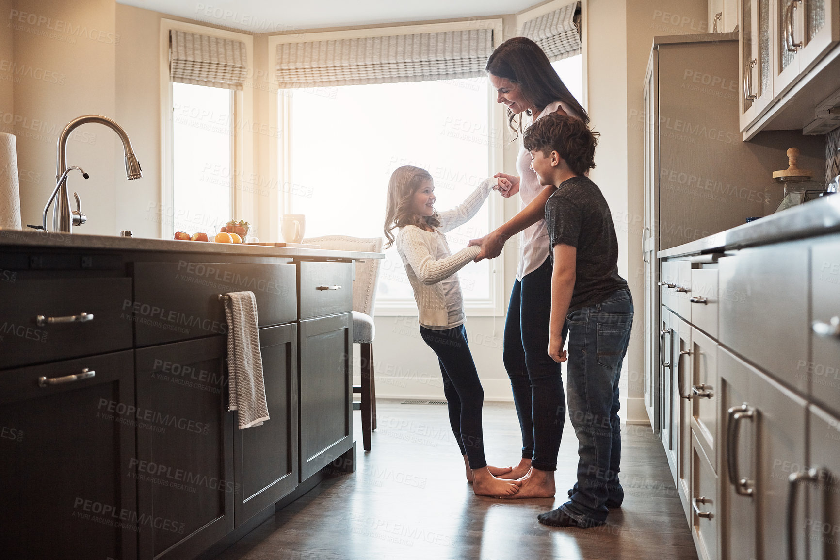 Buy stock photo Love, dance or mother and children in a kitchen for fun, learning and holding hands with trust, care or support at home. Balance, feet and woman with kids in a house for bonding with radio music