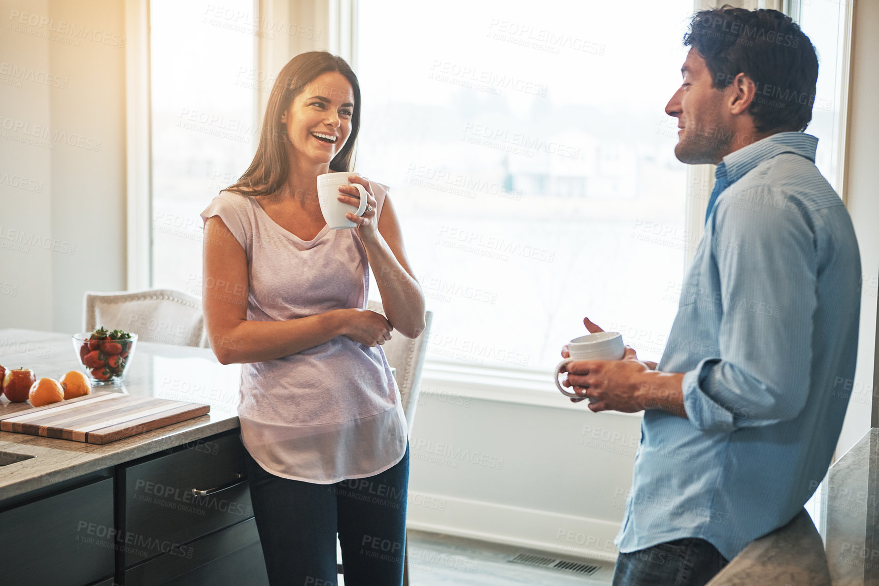 Buy stock photo Shot of a happy married couple chatting while drinking coffee together in their kitchen