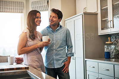 Buy stock photo Shot of a happy married couple chatting while drinking coffee together in their kitchen