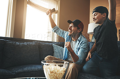 Buy stock photo Shot of a father and son watching a sports match on tv at home