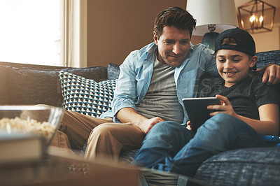 Buy stock photo Shot of a father and his son using a digital tablet together on the sofa at home