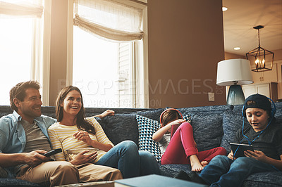 Buy stock photo Shot of a couple watching tv while their kids are busy using digital tablets at home