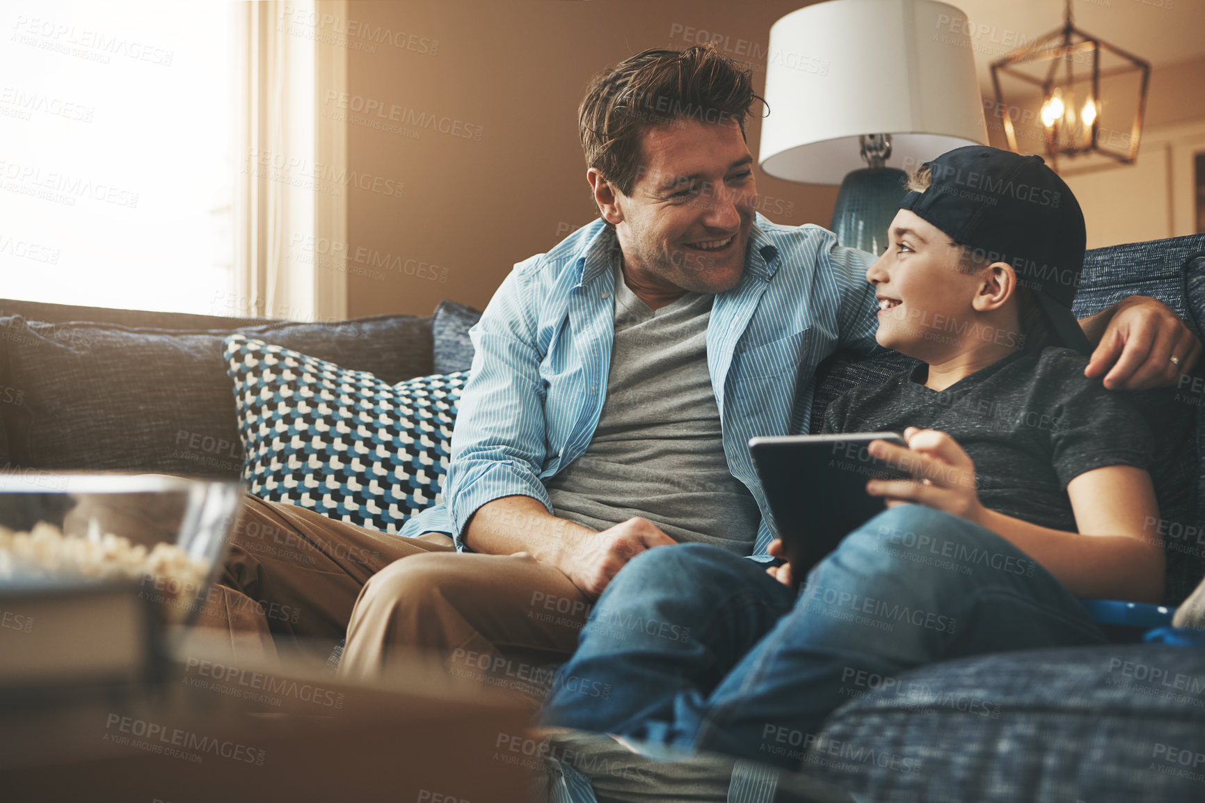 Buy stock photo Shot of a father and his son using a digital tablet together on the sofa at home