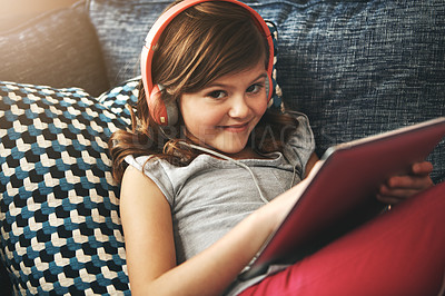 Buy stock photo Portrait of a little girl wearing headphones while using a digital tablet at home