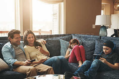 Buy stock photo Shot of a couple watching tv while their kids are busy using digital tablets at home