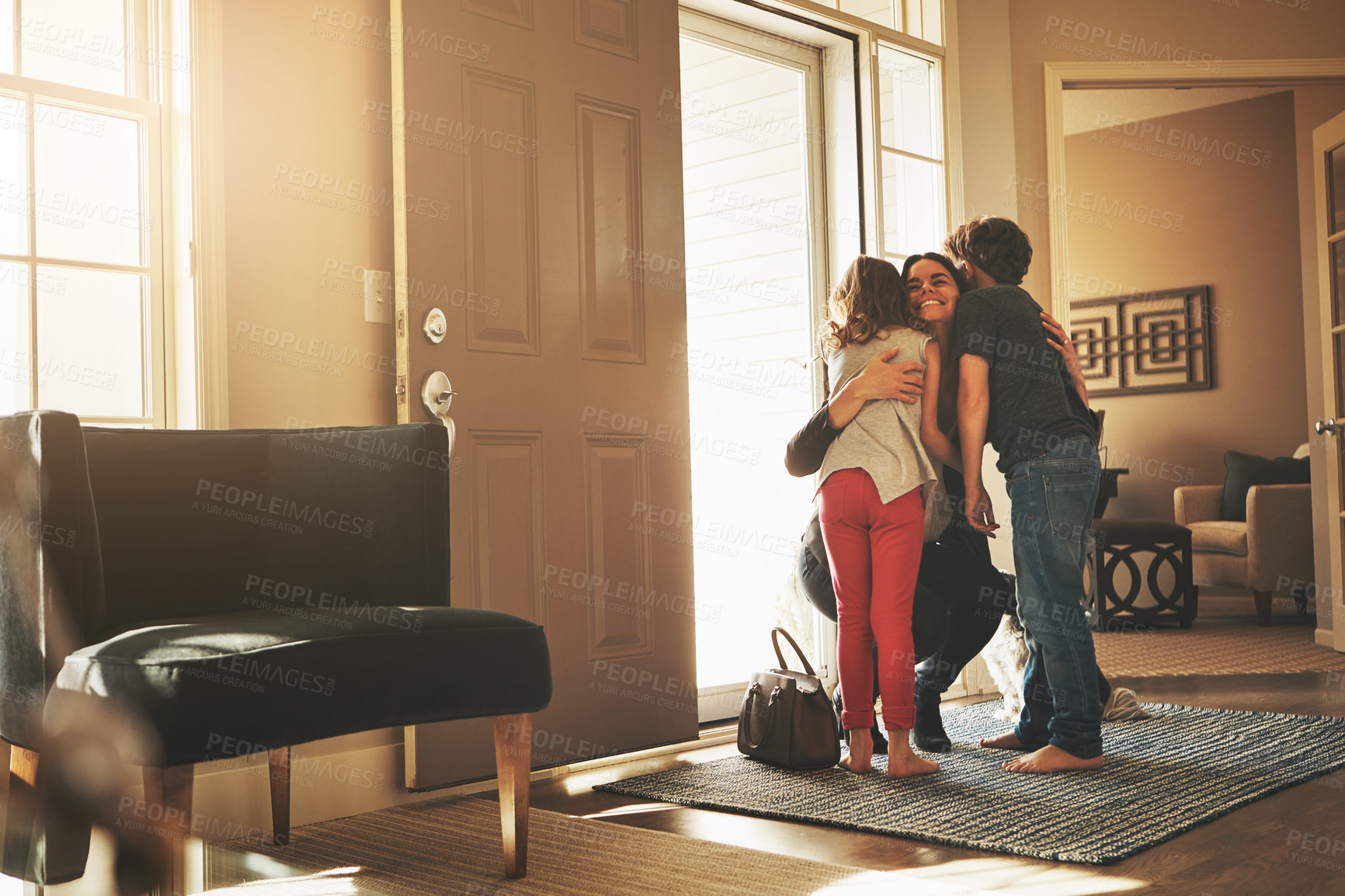 Buy stock photo Home, love and a mother hugging her kids after arriving through the front door after work during the day. Greeting, family or children with a woman holding her son and daughter in the living room