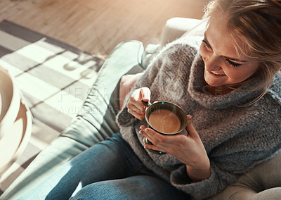 Buy stock photo Shot of a young woman relaxing on the sofa at home with a warm beverage