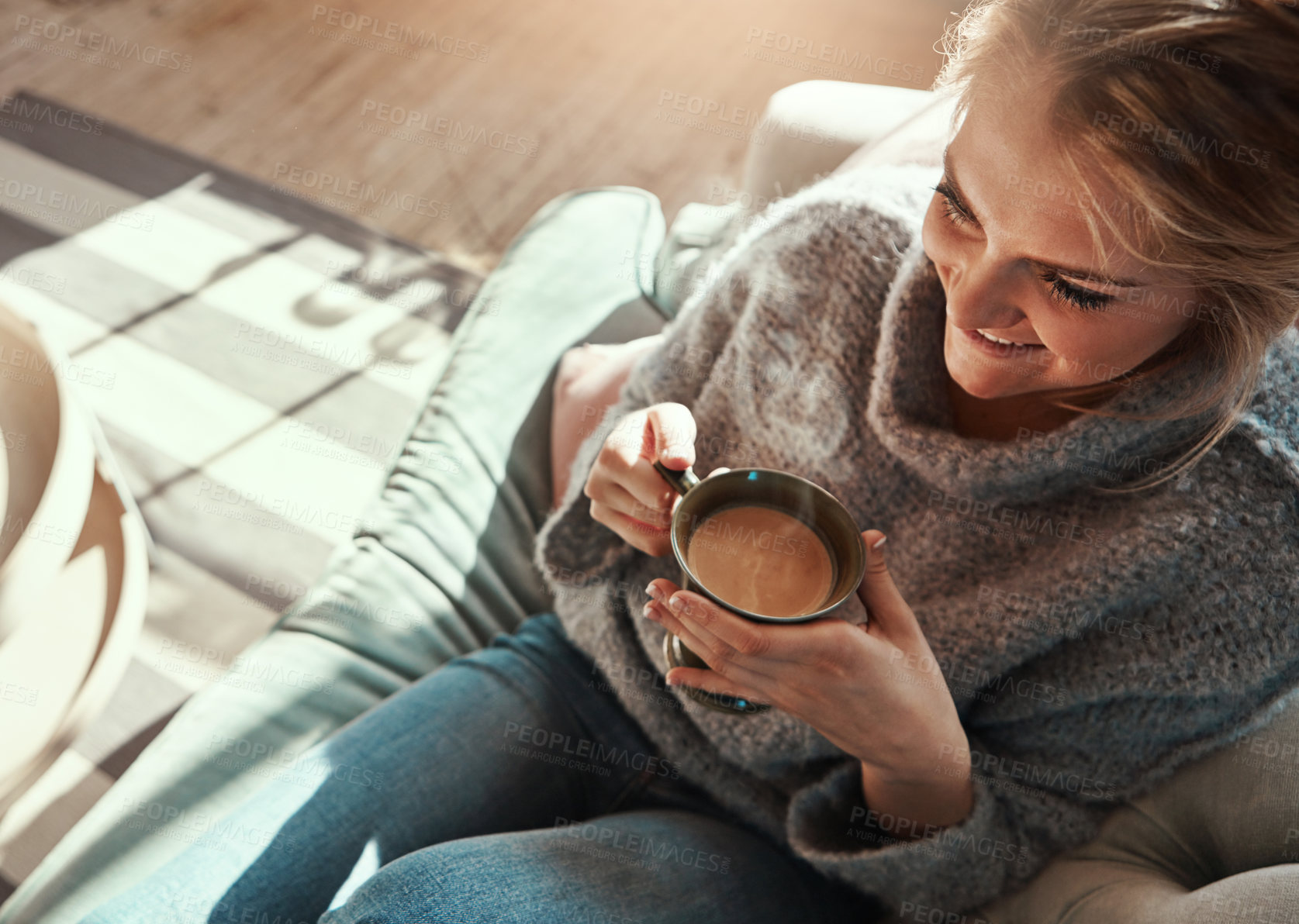 Buy stock photo Shot of a young woman relaxing on the sofa at home with a warm beverage