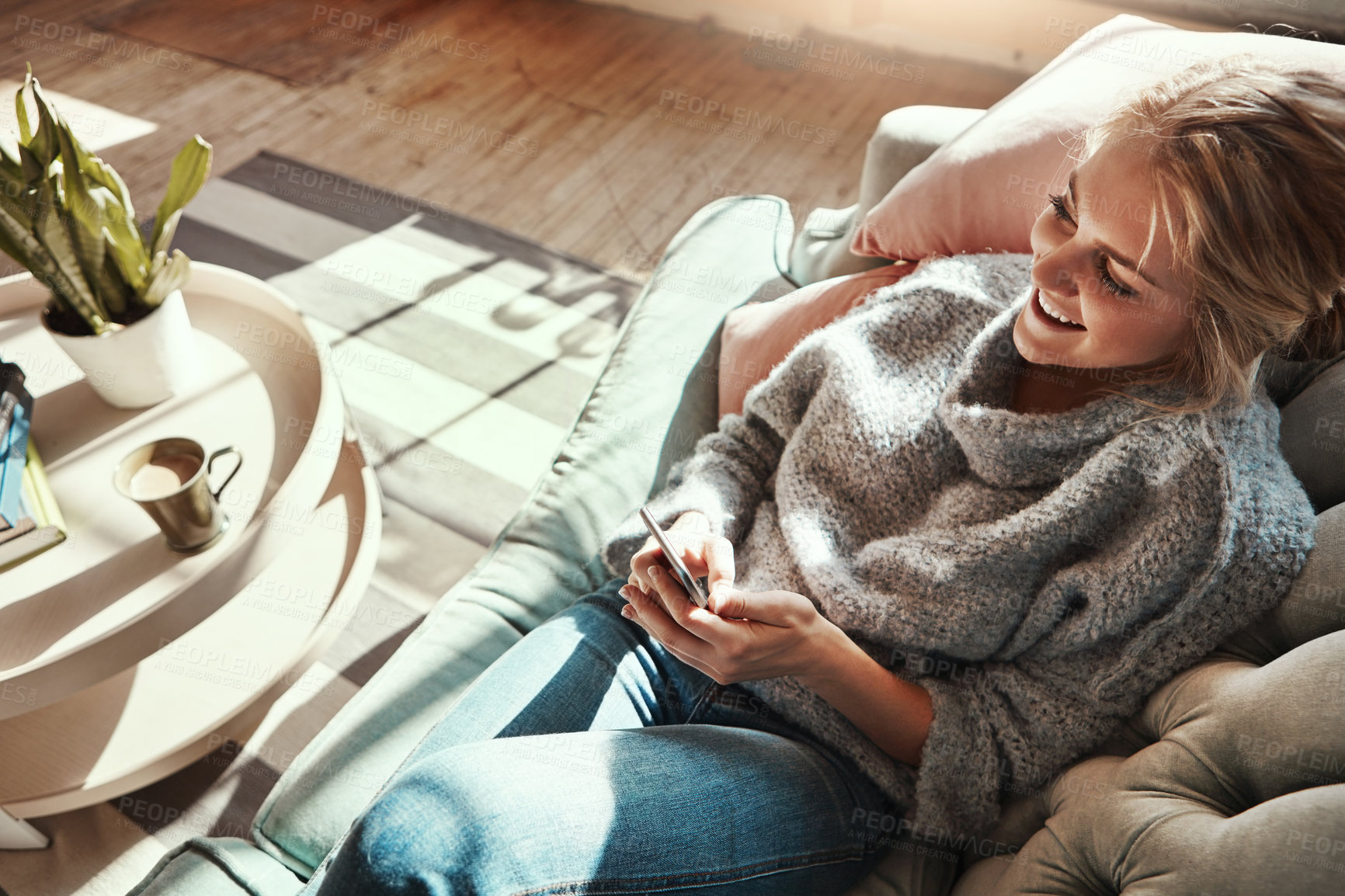 Buy stock photo Phone, relax and happy woman in home for social media, news and reading email in top view. Smartphone, tech and girl on sofa to scroll on app, blog and chat on mobile website online in living room