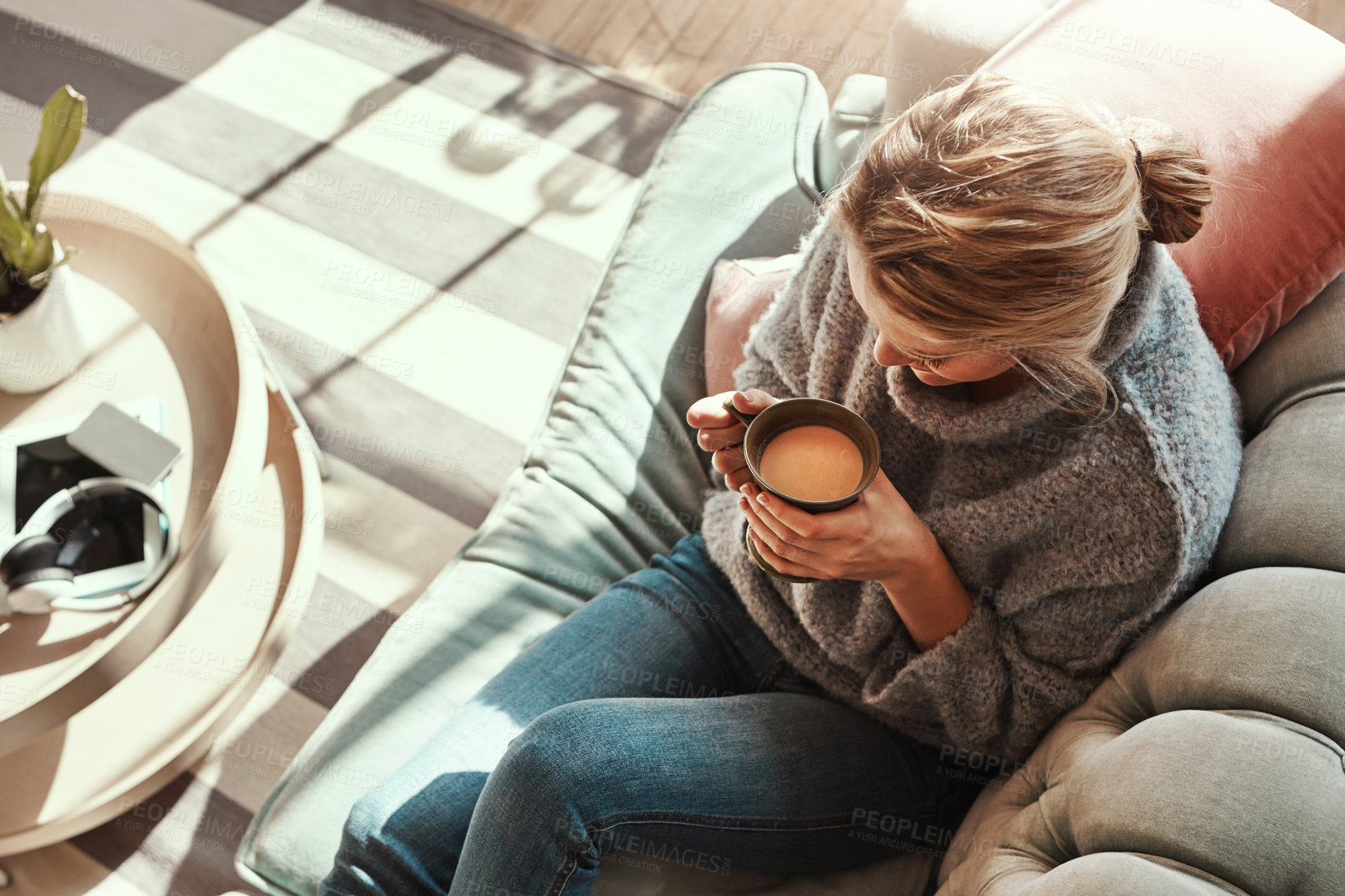 Buy stock photo Shot of a young woman relaxing on the sofa at home with a warm beverage