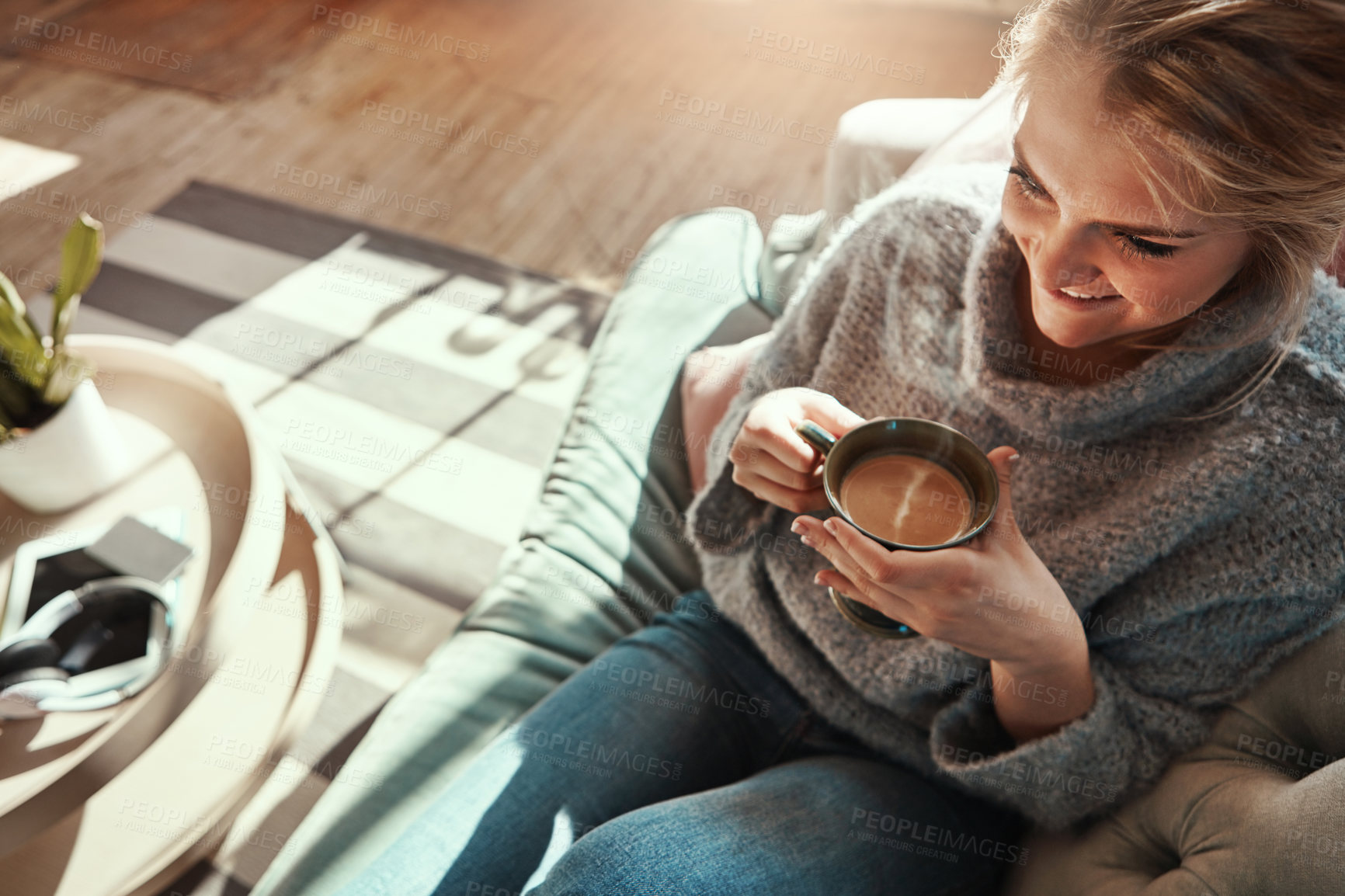 Buy stock photo Shot of a young woman relaxing on the sofa at home with a warm beverage