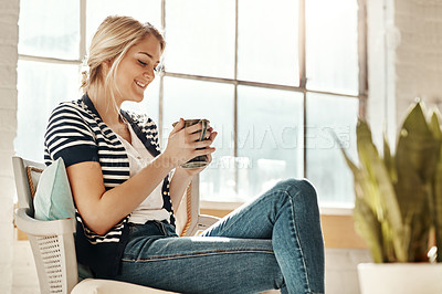 Buy stock photo Shot of a young woman relaxing on a chair at home with a warm beverage