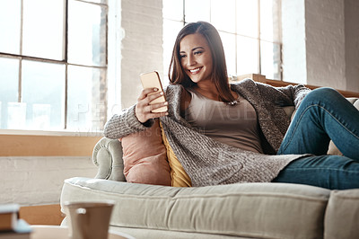 Buy stock photo Woman, phone and relax on sofa for social media, app and text in her home, happy and smile. Girl, smartphone and app for chatting, online dating and internet, search and entertainment in living room