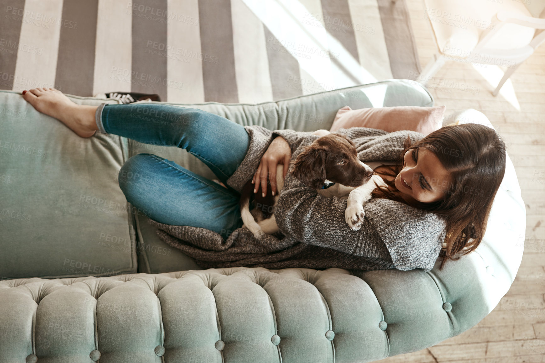 Buy stock photo Smile, bonding and woman with dog on sofa relaxing with pet in living room at apartment. Happy, animal and female person cuddle, hug and embrace puppy with love and care on couch at home from above.