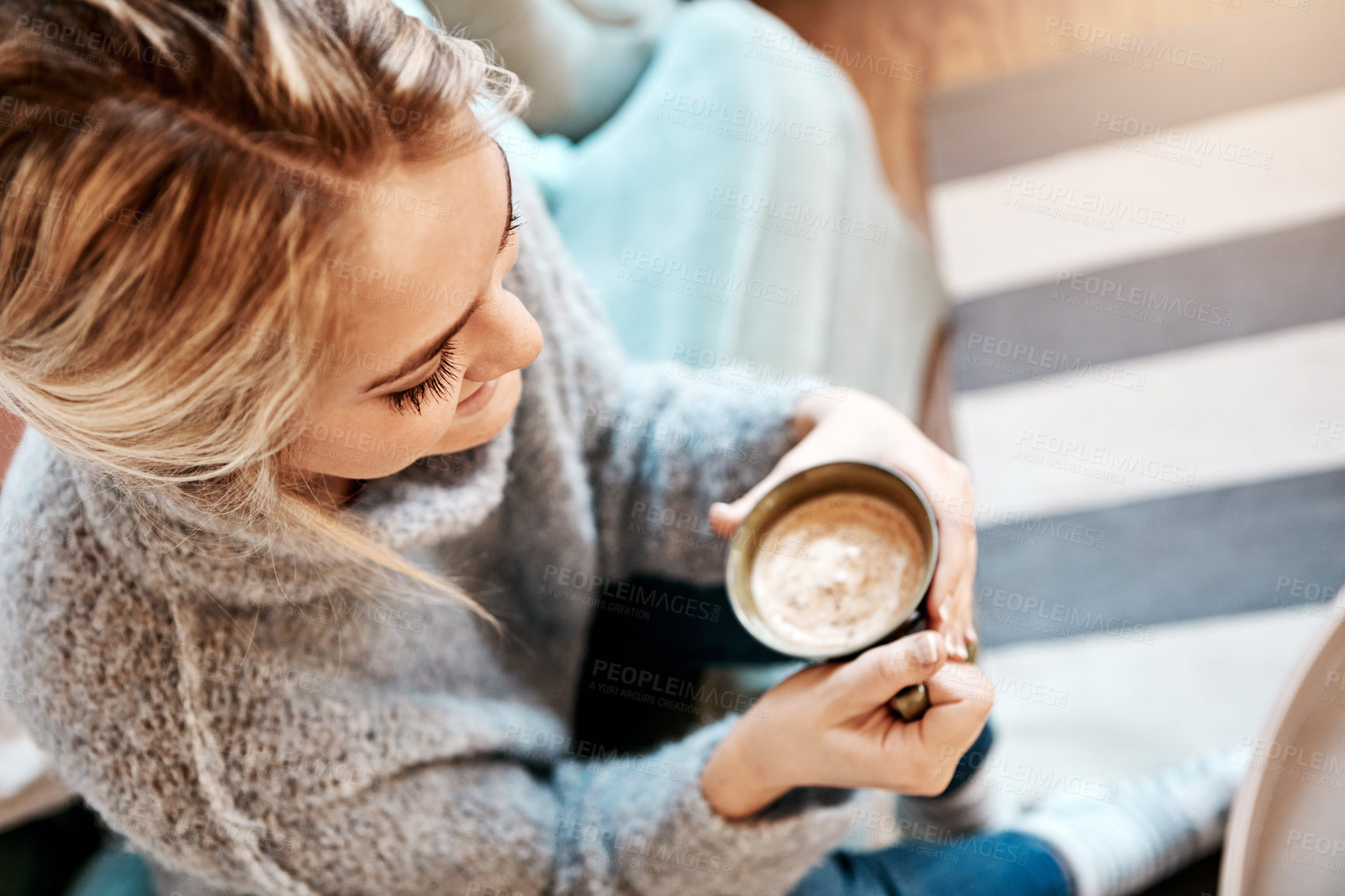 Buy stock photo Shot of a young woman relaxing on the sofa at home with a warm beverage