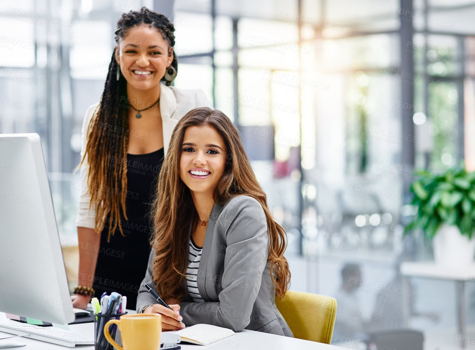 Buy stock photo Cropped portrait of two attractive young businesswomen working at a desk in their office