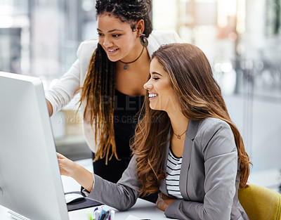 Buy stock photo Cropped shot of two attractive young businesswomen working at a desk in their office