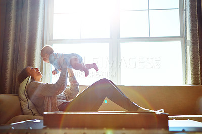 Buy stock photo Shot of a young woman bonding with her baby boy on the sofa at home