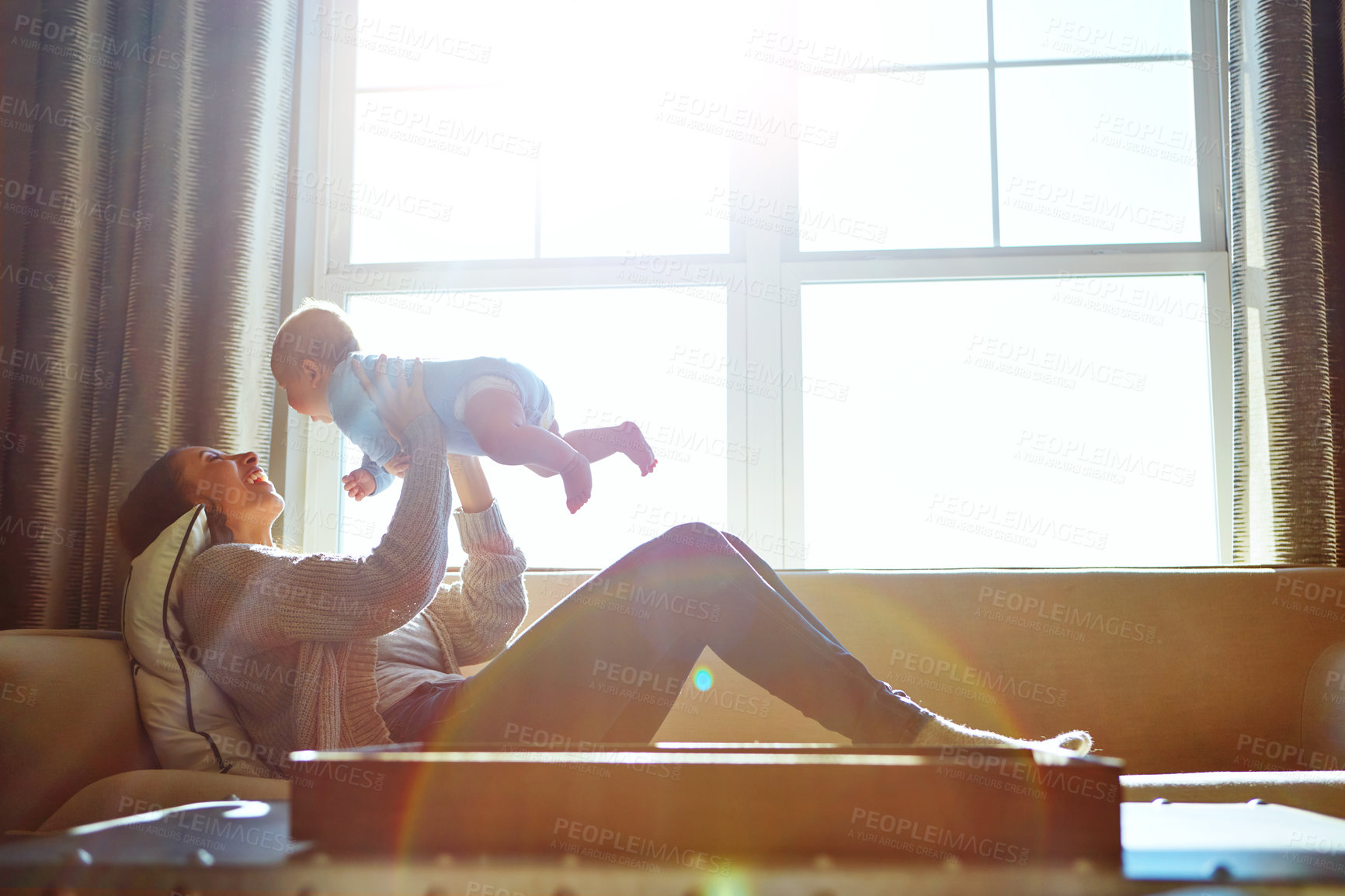 Buy stock photo Shot of a young woman bonding with her baby boy on the sofa at home