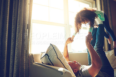 Buy stock photo Shot of a playful father lifting his little girl on his legs while he lies on the couch at home