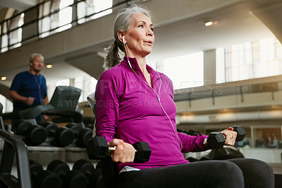 Buy stock photo Fitness, dumbbell and senior woman at a gym for training, wellness and cardio with earphones, music or mindset. Weightlifting, bodybuilding and elderly female person at sports center for arm workout