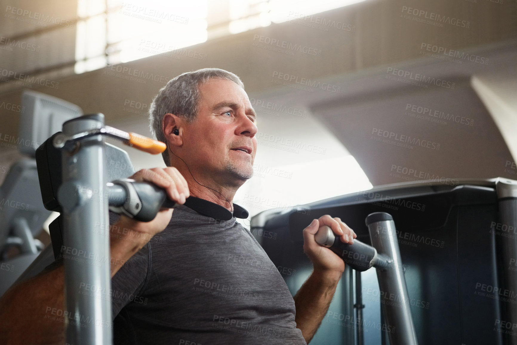 Buy stock photo Mature man, chest press and workout with machine for fitness, training or indoor exercise at gym. Active male person with earphones on equipment for strength, muscle gain or wellness at health club