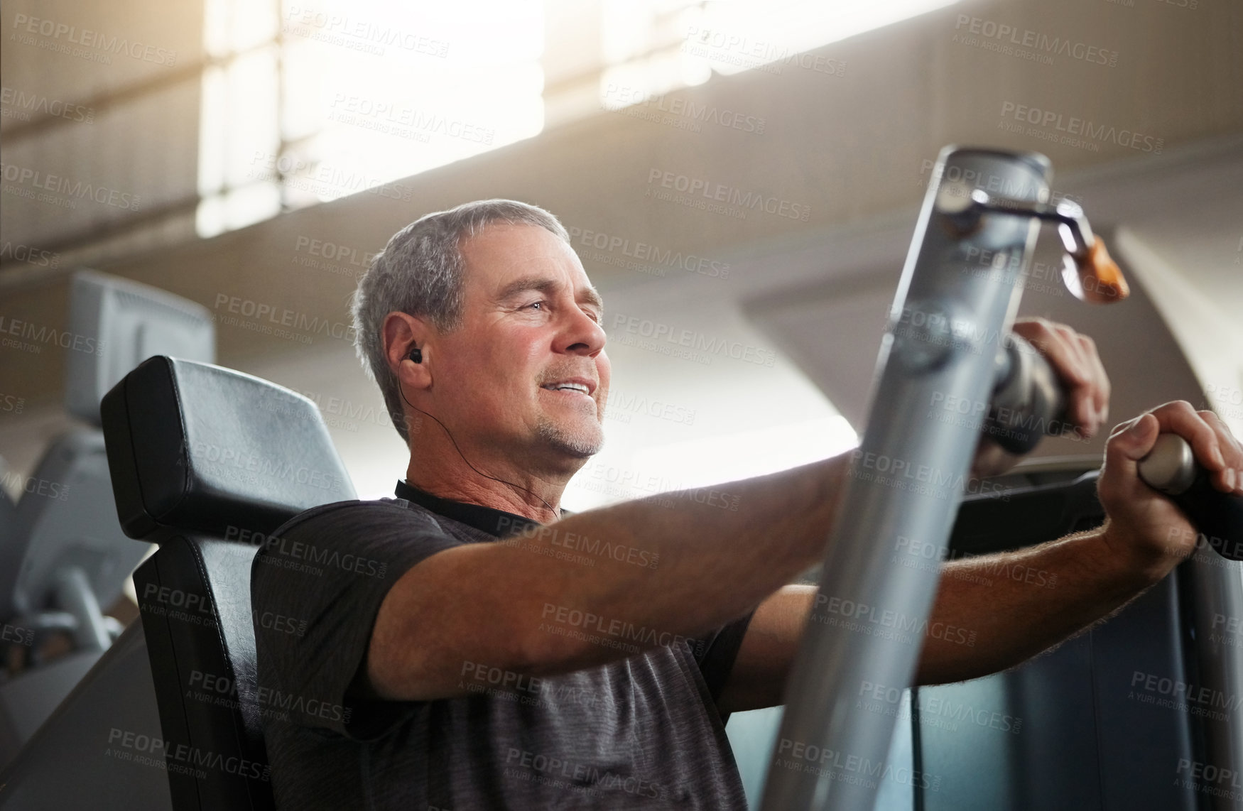 Buy stock photo Mature, happy man and chest press with machine for workout, fitness or indoor exercise at gym. Active male person with earphones on equipment for strength, muscle gain or training at health club
