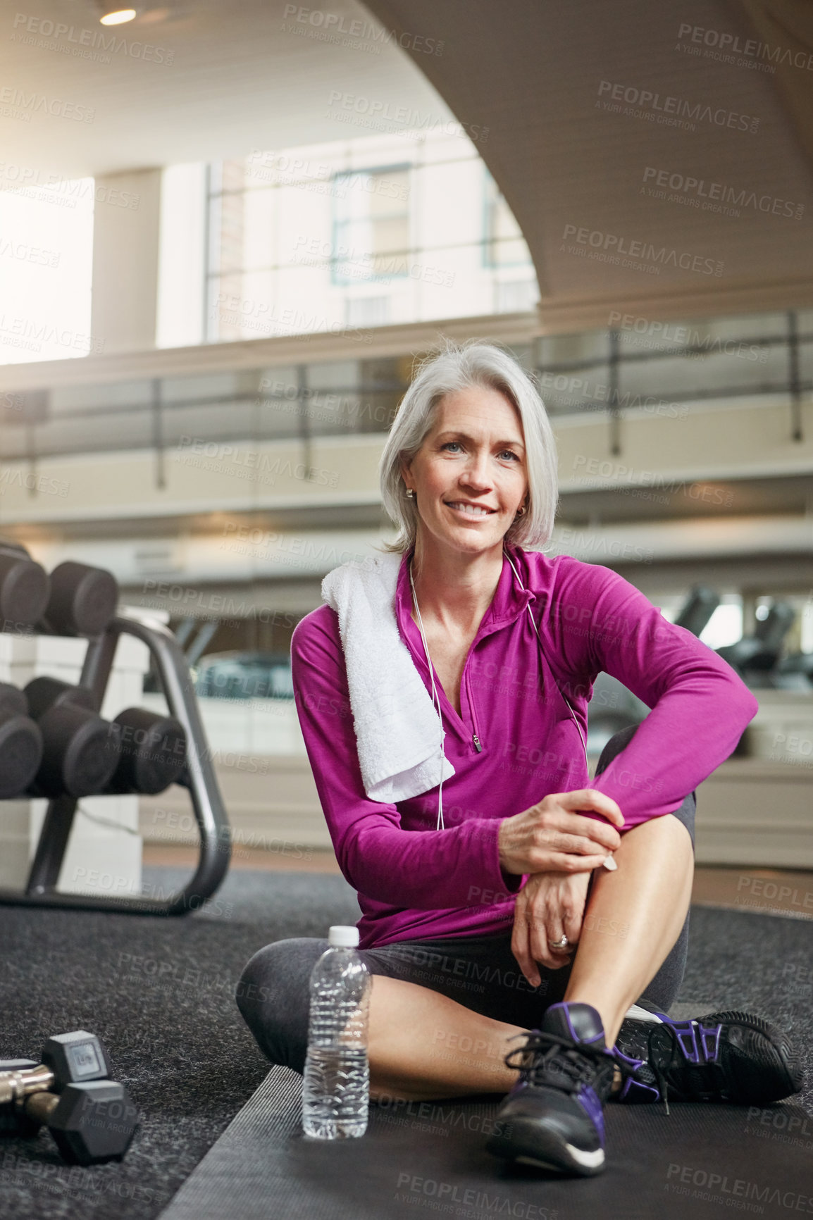 Buy stock photo Gym, floor and portrait of mature happy woman with smile, relax and dumbbells with water bottle at workout. Exercise, training and confident female athlete on break for fitness, health and wellness