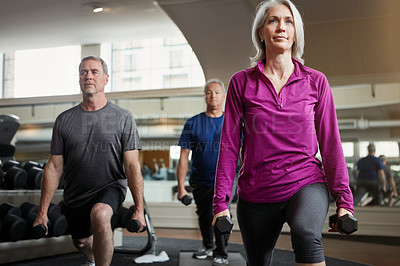 Buy stock photo Shot of a senior group of woman and men working out with weights together at the gym