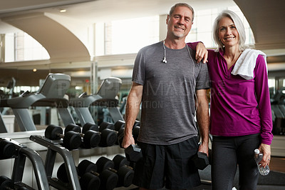 Buy stock photo Shot of a senior married couple smiling and taking a break from their workout at the gym