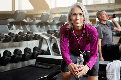 Buy stock photo Shot of a senior married couple working out together at the gym whilst the mature woman takes a break