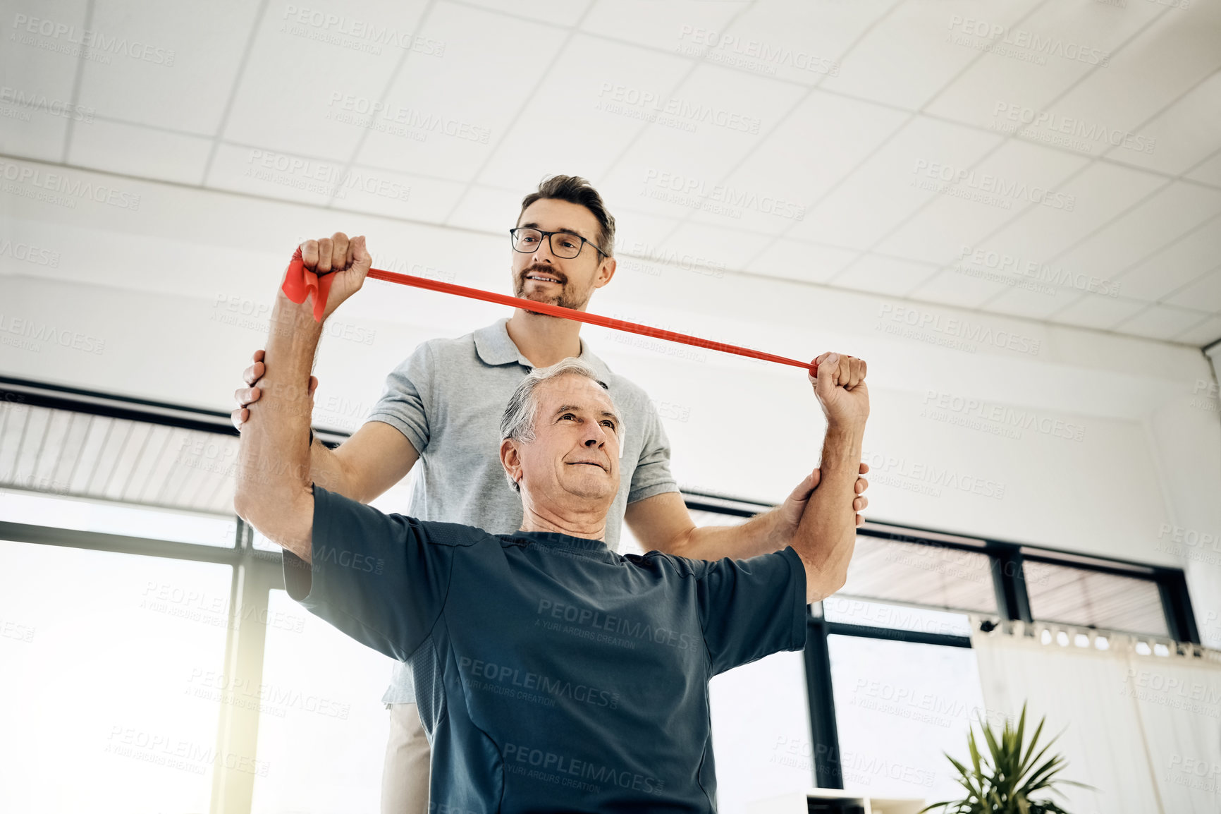 Buy stock photo Exercise, physiotherapist and old man with resistance band, stretching and senior care rehabilitation. Physio, caregiver and elderly patient for mobility training, healthcare and help in retirement.