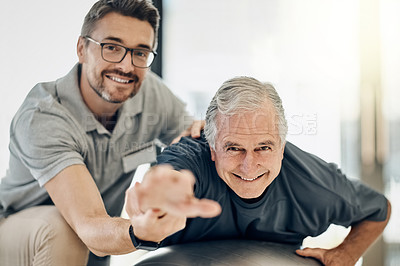 Buy stock photo Shot of a caring physiotherapist helping his mature patient to use a yoga ball at a rehabilitation center