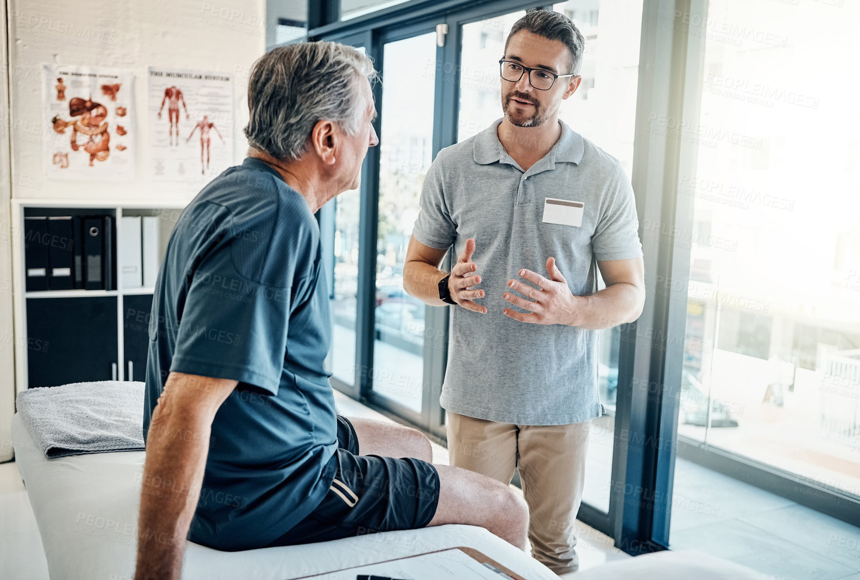 Buy stock photo Shot of a caring physiotherapist consulting with his mature patient in the rehabilitation center