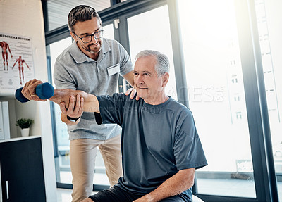 Buy stock photo Shot of a friendly physiotherapist helping his mature patient to lift a dumbbell in the rehabilitation center